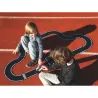 Deux enfants jouent avec un circuit de course noir sur une piste rouge, assemblé comme un parcours sinueux.