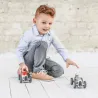 Jeune garçon jouant avec deux voitures miniatures sur un sol blanc, prêt à faire partir la voiture Racing Car Silver,
