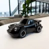 Voiture jouet Porsche 911 Noire de Baghera, petit modèle noir brillant sur table blanche en intérieur.