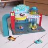 Garage en bois Crazy Motors DJECO 5495: scène de parking pour voitures avec toboggan bleu, porche, pancarte “GARAGE” et petites voitures colorées.