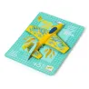 Petit planeur jaune DJECO 2100 "Fire Jet" sur son support de vente turquoise à motifs, avec ailes décoratives et queue bleue.