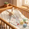 Doudou lapin SIGIKID 31269 en peluche éponge beige et tissu à fleurs dans un lit bébé en bois.