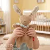 Doudou lapin marron SIGIKID 31268 en tissu éponge, enfant tenant la peluche avec un foulard, chambre de bébé en arrière-plan.