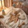 Doudou lapin marron SIGIKID 31268 en tissu éponge posé dans lit bébé avec étoile, nuages et jouets pastel.