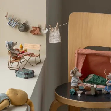 Une souris Maileg assise sur sa chaise de jardin, mise en situation sur un appui de fenêtre et accessoires Maileg