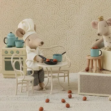 Chef cuisinier souris Maileg sert un plat à table, cuisinière en arrière plan