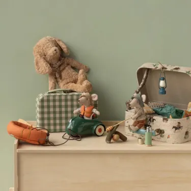 Le bateau pneumatique orange Maileg tracté par le tricycle vert et sa souris portant son gilet. Décor Maileg avec pêcheur, peluche chien et valisette.