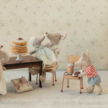 Bébé souris Maileg dans les bras de son papa assis à table avec gâteau et cadeau.