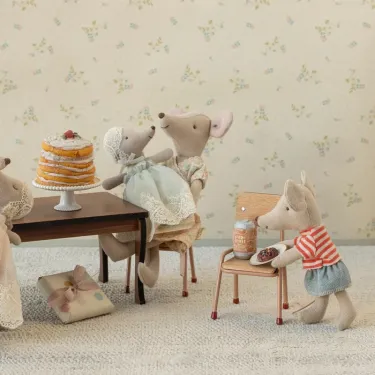 Bébé souris Maileg dans les bras de son papa assis à table avec gâteau et cadeau.