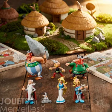 Tubo ASTERIX Village - 7 figurines PLASTOY: personnages en figurine miniatures posés sur une table, avec maisons village gaulois en arrière-plan.