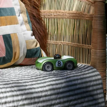 Voiture de course Viglietta Playforever Birdy, mini modèle vert portant le numéro 8 sur un drapeau blanc et noir sur un canapé en osier.