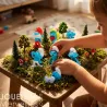 Miniature Schtroumpfs en figurines plastoy sur un décor forestier, enfants manipulant les lutins au milieu des arbres et champignons.