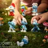 Mini Schtroumpfs en figurines Tubo Plastoy – 7 personnages Schtroumpfs, posés dans une clairière avec des mains d'enfants les manipulant.