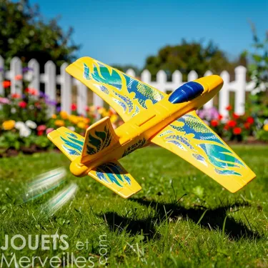 Petit planeur jaune DJECO 2100 "Fire Jet" lors d’un envol dans un jardin, traces de propulsion et motifs bleus.