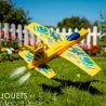 Petit planeur jaune DJECO 2100 "Fire Jet" lors d’un envol dans un jardin, traces de propulsion et motifs bleus.
