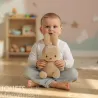Peluche Miffy en velours côtelé beige de 23 cm tenue par un bébé assis sur le sol, intérieur doux et lumineux.