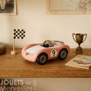 Voiture de course Viglietta Playforever Dottie, design vintage rose avec numéro 9 sur table en bois, miniature près d’un drapeau à damier et d’un trophée.