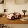 Voiture de course Viglietta Playforever Dottie, design vintage rose avec numéro 9 sur table en bois, miniature près d’un drapeau à damier et d’un trophée.