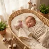 Doudou mésange rose en coton bio, bébé endormi dans un lit en osier, peluche crochetée et couverture crème à côté.