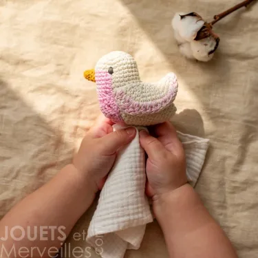 Doudou mésange rose en coton bio à crochet, main d'enfant tenant ce doudou Myum.
