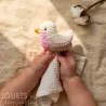 Doudou mésange rose en coton bio à crochet, main d'enfant tenant ce doudou Myum.