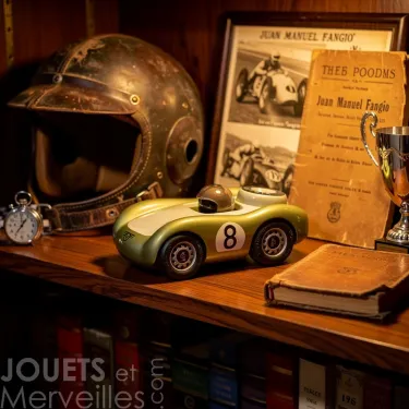 Voiture de course Viglietta Playforever Birdy vintage sur étagère, entourée d’un casque, livre ancien et trophée, ambiance bibliothèque vintage.