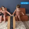 Deux enfants jouent avec le Circuit de route flexible Waytoplay sur une table, utilisant 2 voitures jaunes et bleues sur une route nationale. Coffret de 16 pièces visible.