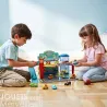 Deux enfants jouent avec un garage en bois Crazy Motors DJECO 5495, voitures miniatures et parking sur un plateau coloré posé au sol.