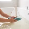 Sloop Tirot : petit voilier en bois blanc et bleu, mains d’enfant tenant le bateau flottant sur l’eau dans une baignoire.