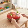 Tambour à languettes rouge métallique DJECO 6039 posé sur une table, deux baguettes frappant les touches colorées.