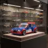 Modèle miniature Renault 5 Maxi Turbo Belu et rouge exposé dans une vitrine sur socle, avec fond de petites voitures en arrière-plan.
