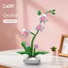 Orchidée CADA 237 pièces: plante florale anti-stress en briques, tige verte, fleurs orchidées blanches et roses, base ronde blanche sur bureau pastel.