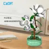 Camellia CADA 301 pièces : set de construction florale décoratif avec arbre en briques mint et fleurs blanches sur socle vert, sur table.