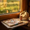 Jeu de labyrinthe à billes magnétique "Cirque" sur une table, près d’un sac à dos dans un compartiment de train.