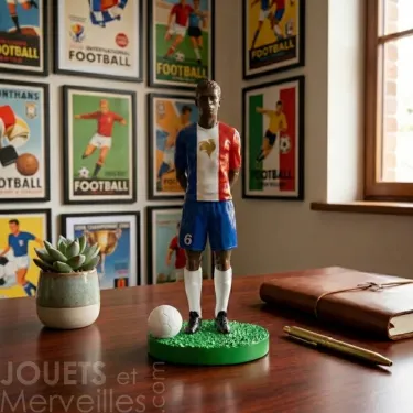 Figurine footballeur black en résine aux couleurs de la France de marque Match Day Fan Club posée sur un bureau avec affiche de football vintage en arrière plan