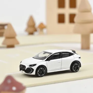 Miniature Renault Clio VI 2026 NOREV 1/64 en blanc Glacier sur route miniature, fond village en bois.