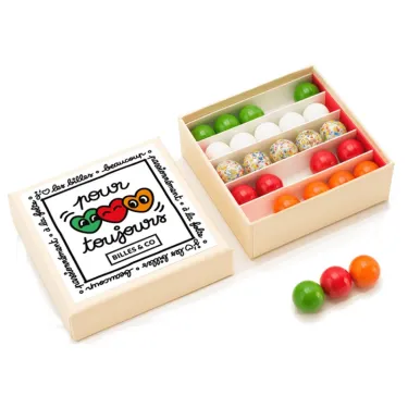 Petit coffret de billes "Pour toujours" Billes & Co, boîte ouverte montrant plusieurs rangées de billes colorées et une série de billes dehors.