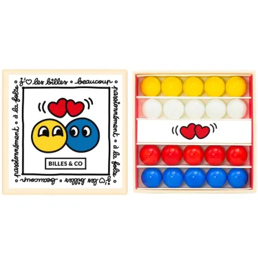 Petit coffret de billes Amour Billes & Co: écrin en carton avec cinq billes jaunes sur le dessus et rangées de billes rouges, bleues et blanches à l’intérieur.