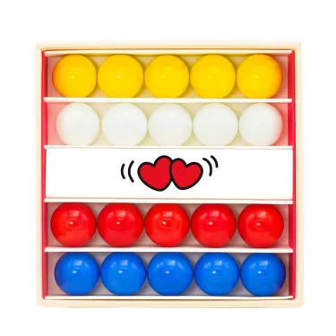 Petit coffret de billes Amour Billes & Co: rangées de billes jaunes, blanches, rouges et bleues dans une boîte en carton avec un motif de cœurs.