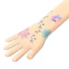 Tatouages éphémères « Belle des champs » DJECO 9585: avant-bras décoré de fleurs pastel et d’un papillon.