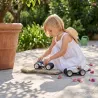 Petite fille en robe blanche joue avec des voitures miniatures Racing Car Bleue, N°2 et N°3 sur une terrasse en pierre, jardinière en terre cuite à l'arrière.