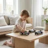 Petit garçon jouant avec des voitures miniatures sur une table en bois dans un salon lumineux.