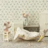 Chaise haute pour bébé souris Maileg, décor de chambre blanche crème avec souris en peluche, petite table, linge et linge de lit à motifs bleus.