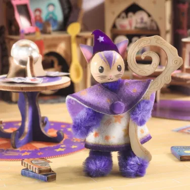 Petit personnage peluche violet astral, robe étoilée et cape, dégainant une cane magique, dans un décor de maison de poupée Maison Mi House - Astra.