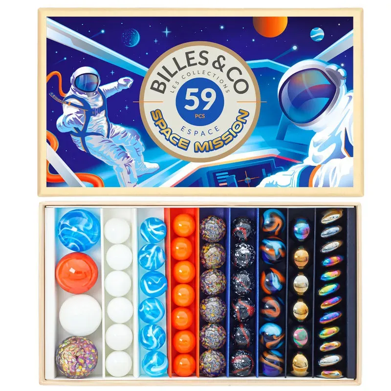 Boîte de billes & Co "Space Mission" avec 59 pièces: planètes et billes colorées rangées par compartiments sous un couvercle illustré astronaute et cosmos.