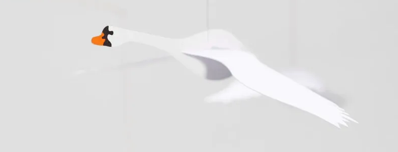 Cygne blanc en papier, en vol, en silhouette légère sur fond clair avec bec orange, détail d'un mobile Flensted..