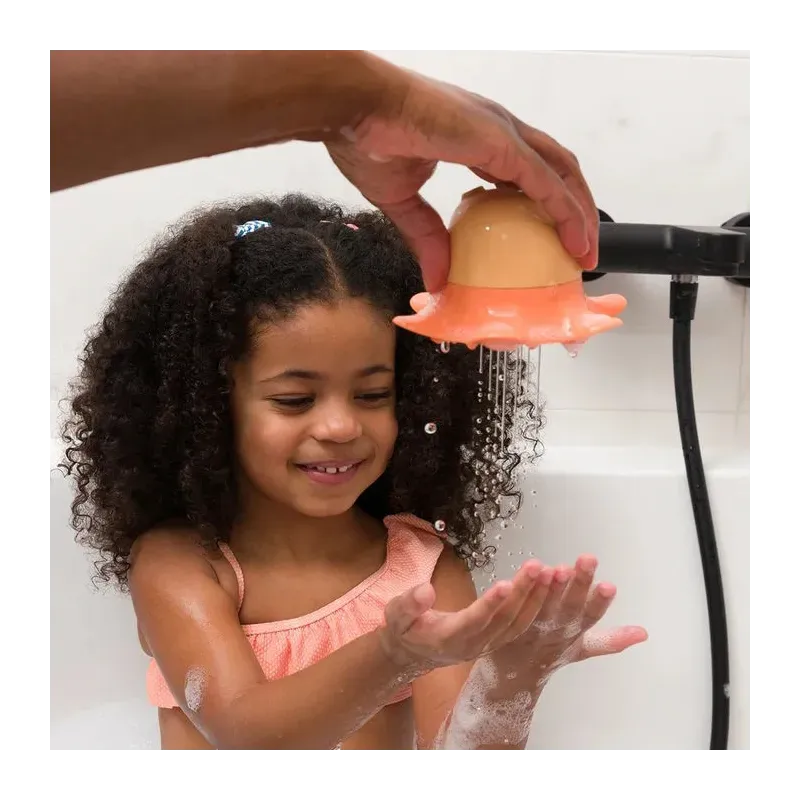 Jeune fille souriante dans son bain, joue avec un jouet pour le bain en forme de poulpe.