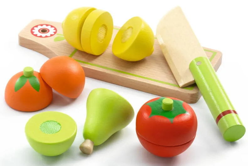 Jouet en bois pour préparation culinaire avec légumes colorés et couteau en bois sur planche.