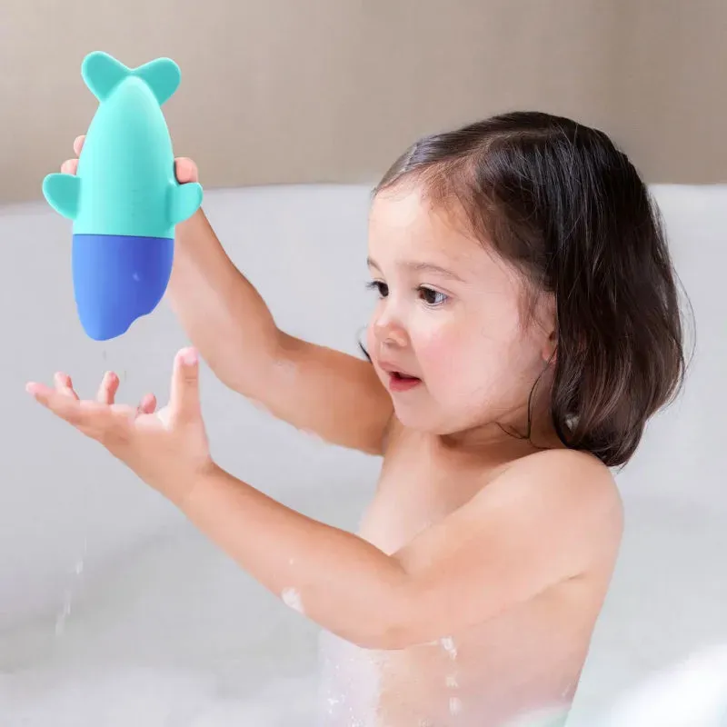 Jouet d’éveil souple en forme d’animal turquoise et bleu, jeune enfant joyeusement manipulant le jouet sous l’eau.